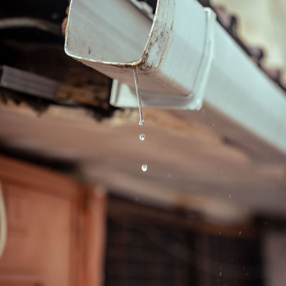Water dripping from the end of a white gutter
