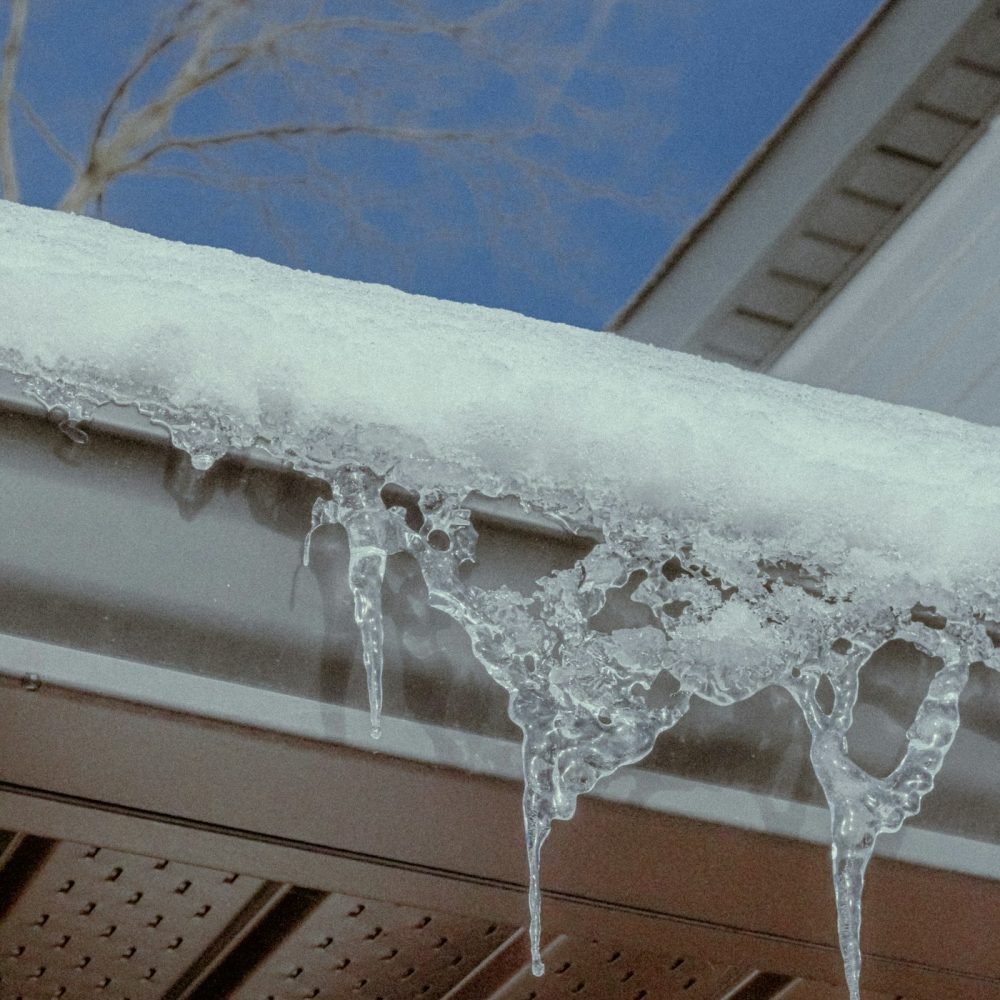 Snow and ice packed along a gutter with icicles hanging from the edge